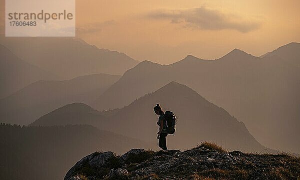 Abendstimmung  Bergsilhouetten  Wanderer vor Hügellandschaft  Berge und Landschaft  Bayrische Voralpenlandschaft  Benediktbeuern  Bayern  Deutschland  Europa