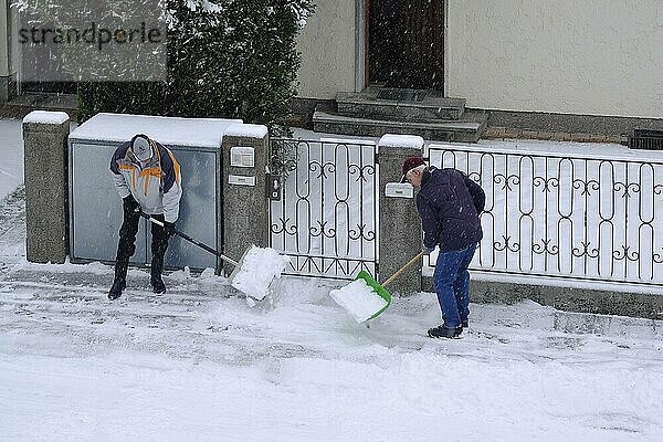 Zwei Männer beim räumen von Schnee vom Bürgersteig  München  Bayern  Deutschland  Europa
