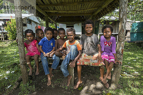 Kinder sitzen auf einer Bank auf Kitava auf den Trobriand-Inseln  Papua-Neuguinea; Kitava Island  Trobriand-Inseln  Papua-Neuguinea