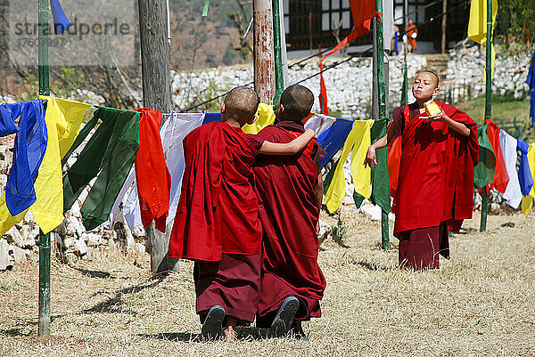 Zwei junge Mönche spazieren während des bhutanischen Paro Tshechu Festivals in Paro Dzong  einem Kloster und einer Festung in Paro  Bhutan; Paro  Bhutan