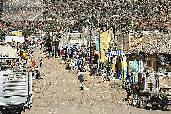 Dorf im ländlichen Äthiopien und Fußgänger auf einem von Gebäuden gesäumten Feldweg; Äthiopien