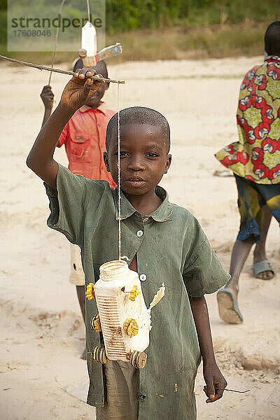 Ein Junge posiert mit einer Plastikflasche  die er in ein Spielzeugauto verwandelt hat; Lower Zaire River  in der Nähe von Luozi  Demokratische Republik Kongo.