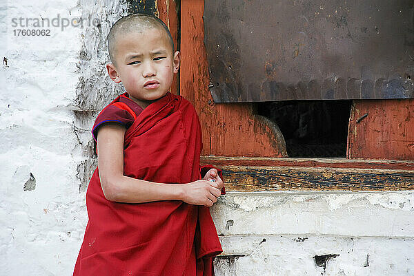Junger Mönch lehnt an einer Wand im Paro Dzong  einem buddhistischen Kloster und einer Festung in Paro  Bhutan; Paro  Bhutan