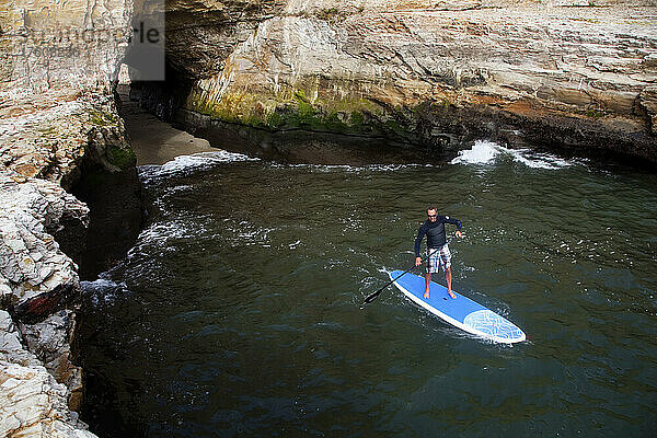 Ein Stand Up Paddleboarder an der rauen Küste nördlich von Santa Cruz.