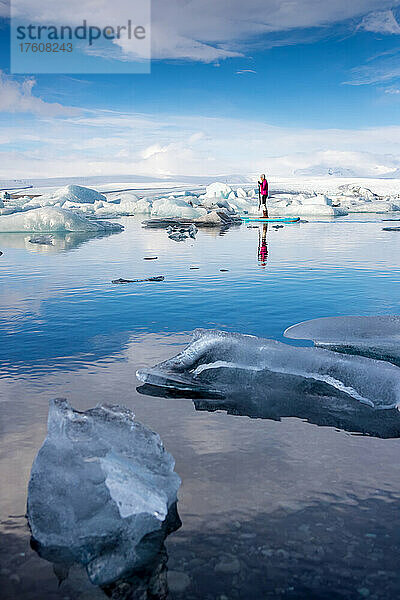 Eine Frau auf einem aufblasbaren Paddleboard paddelt auf der Lagune des Jokulsarlon-Gletschers.