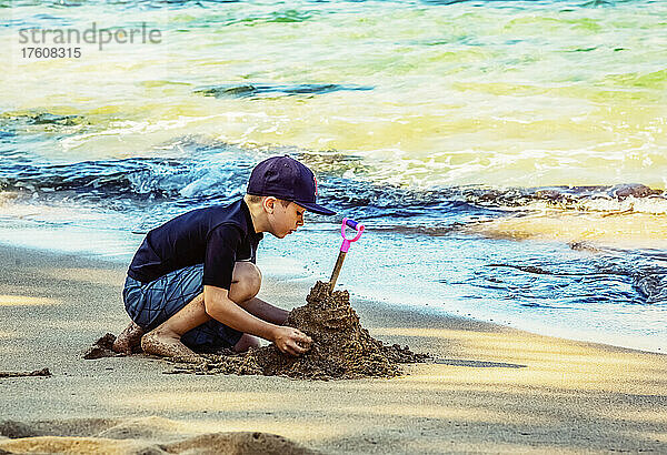 Ein kleiner Junge spielt am Strand der Kapalua Bay im Sand am Rande des Wassers; Kapalua  Maui  Hawaii  Vereinigte Staaten von Amerika