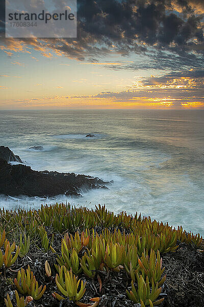 Praia do Carvalhal mit einem dramatischen Sonnenaufgang über dem Horizont; Alentejo  Portugal