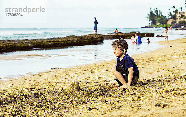 Ein kleiner Junge sitzt am Strand von Ka'alapali im Sand und blickt auf den Ozean; Ka'anapali  Maui  Hawaii  Vereinigte Staaten von Amerika