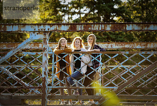 Außenporträt einer Mutter mit zwei Töchtern auf einer Brücke in einem Stadtpark; Edmonton  Alberta  Kanada