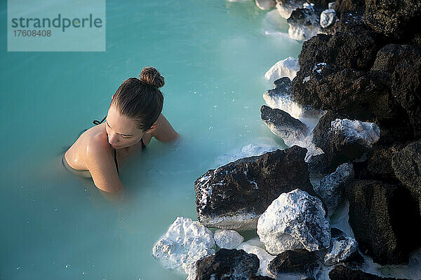 Eine Frau schwimmt in der blauen Lagune von Island.