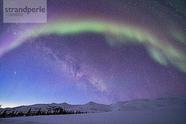 Aurora borealis (oder Nordlicht) über dem Dempster Highway und den schneebedeckten Bergen am Sternenhimmel im Winter; Yukon  Kanada