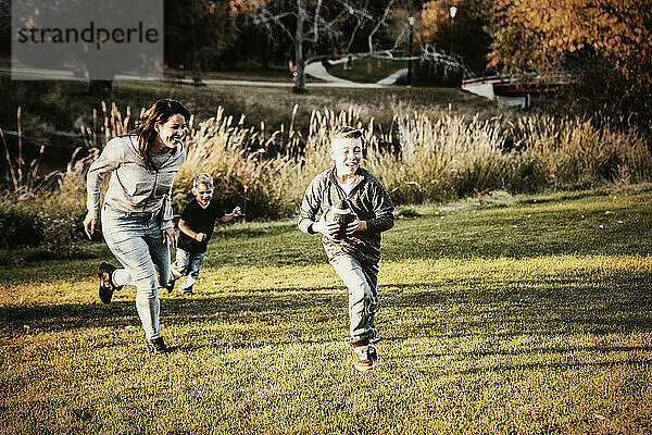 Mutter  die ihren Sohn an einem schönen Herbsttag in einem Stadtpark mit einem Fußballspiel verfolgt; St. Alberta  Alberta  Kanada