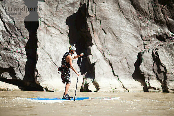 Ein Mann surft auf seinem Stand-up-Paddleboard auf dem Colorado River in einem Abschnitt namens Westwater.