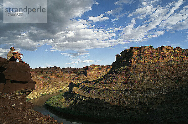Wanderer sitzt am Rande einer Klippe und überblickt den Colorado River; Cataract Canyon  Utah.