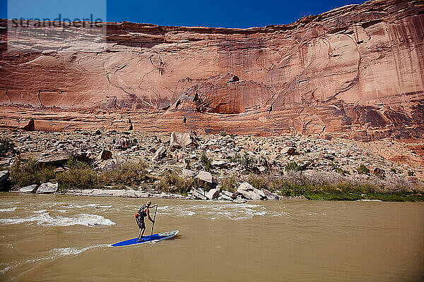 Ein Mann surft mit seinem Stand-up-Paddleboard auf dem Colorado River in einem Abschnitt namens Westwater .