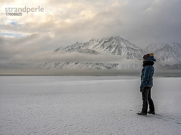 Frau steht am gefrorenen Ufer des Kathleen Lake und blickt auf die stimmungsvolle Landschaft; Haines Junction  Yukon  Kanada