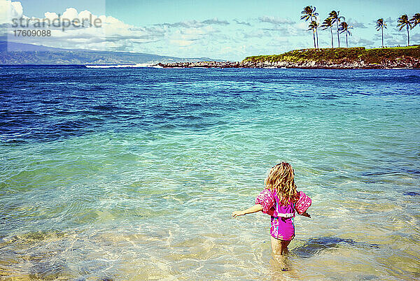 Ein junges Mädchen watet am Kapalua Beach in der Kapalua Bay mit der Insel Molokai im Hintergrund ins Meer; Kapalua Beach  Maui  Hawaii  Vereinigte Staaten von Amerika