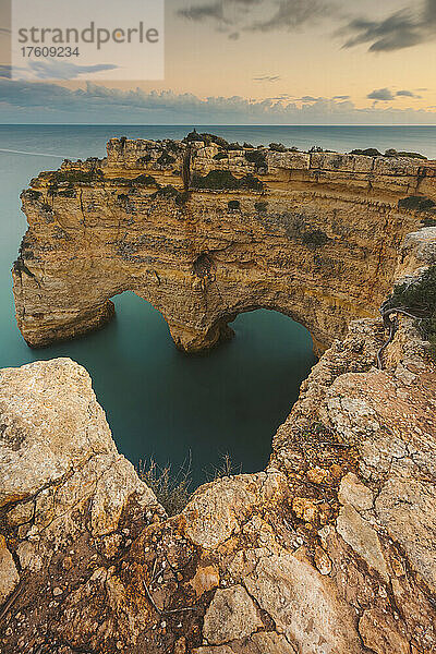 Ikonische Felsformation  Arcos Naturais  Herz der Algarve  und das türkisfarbene Wasser des Atlantiks am Praia da Marinha entlang der Atlantikküste in Caramujeira  Teil der Gemeinde Lagoa  bei Sonnenuntergang; Algarve  Bezirk Faro  Portugal