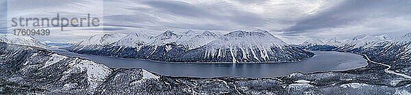 Panoramaluftbild des Tutshi-Sees an einem grauen Tag mit dramatischen Wolken und schneebedeckten Bergen im Winter; Yukon  Kanada