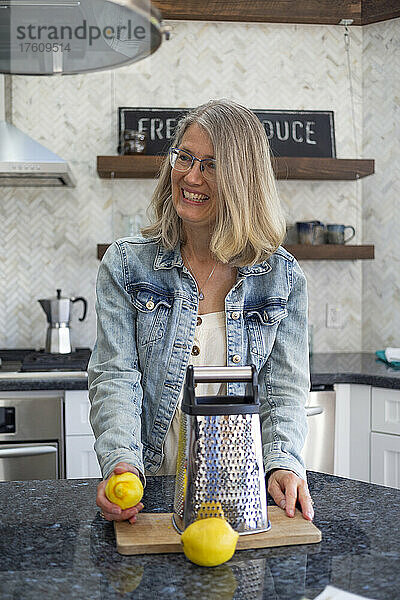 Eine reife Frau steht in ihrer Küche mit frischen Zitronen und einer Reibe; Kelowna  British Columbia  Kanada