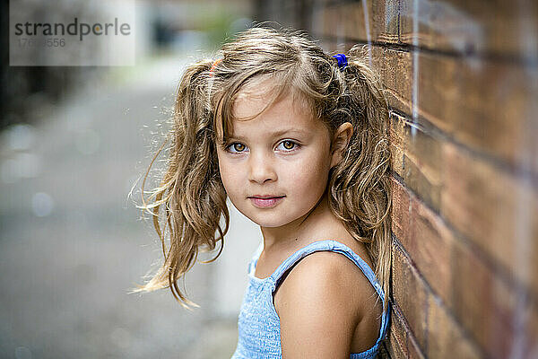 Außenporträt eines jungen Mädchens  das in einer Gasse an einer Backsteinmauer steht; Toronto  Ontario  Kanada