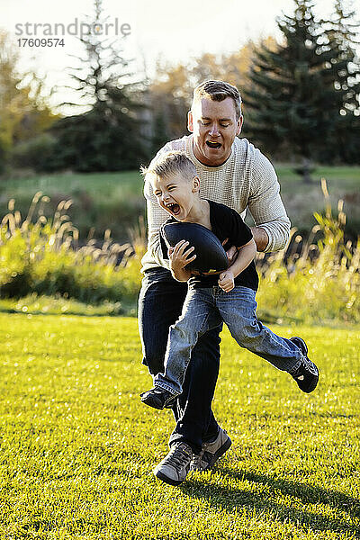 Vater spielt Fußball mit seinem kleinen Sohn in einem Park im Herbst; St. Albert  Alberta  Kanada