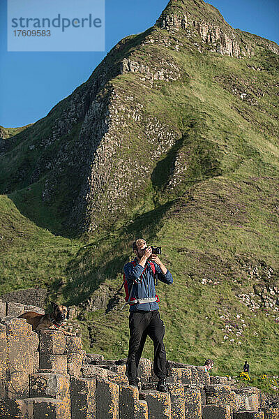 Ein junger Mann und sein Hund erkunden den Giant's Causeway in Nordirland  Vereinigtes Königreich.