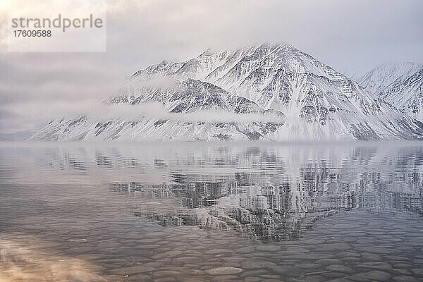 Der schneebedeckte Mount Worthington spiegelt sich in den stillen Wassern des Kathleen Lake  wobei neblige  tiefhängende Wolken und gedämpfte Farben eine stimmungsvolle Atmosphäre schaffen; Haines Junction  Yukon  Kanada