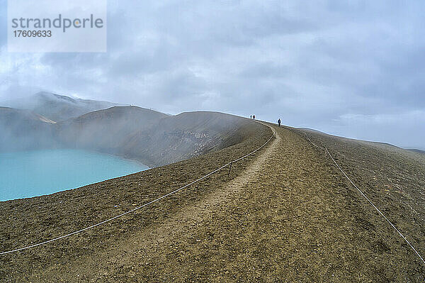 Touristen spazieren am Rand des türkisfarbenen Kratersees des Kraters Viti am Vulkan Krafla in der Region Myvatn in der nördlichen Region Islands; Krafla  Nordurland Vestra  Island