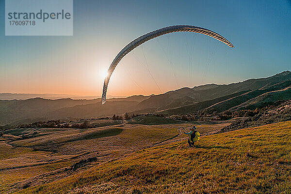 Gleitschirmpilot spielt mit seinem Flügel  während die Sonne untergeht; San Ynez Valley  Kalifornien  Vereinigte Staaten von Amerika