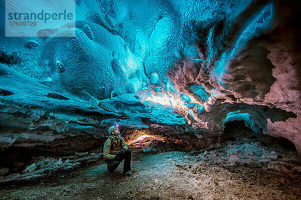 Ein Mann blickt in einer Gletscherhöhle auf das Eis.