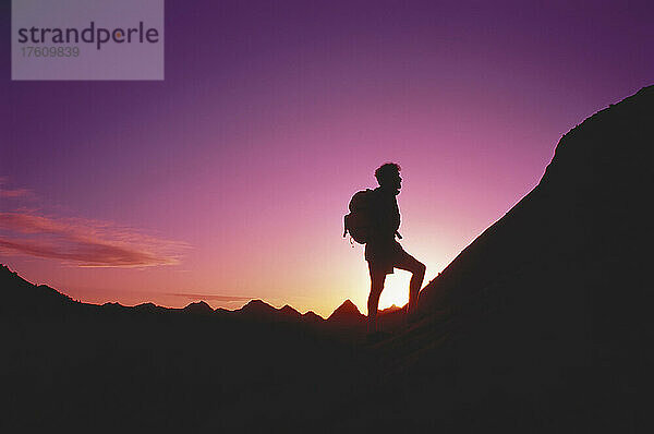 Silhouette eines Mannes beim Wandern unterhalb der weißen Klippen bei Sonnenuntergang Zion National Park  Utah  USA