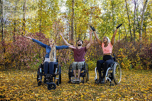 Gruppe von drei jungen Querschnittsgelähmten in ihren Rollstühlen in einem Park an einem schönen Herbsttag; Edmonton  Alberta  Kanada