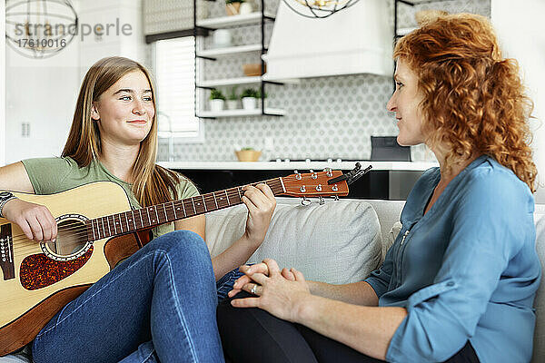 Mutter und Tochter im Teenageralter verbringen gemeinsam Zeit zu Hause  während die Tochter Gitarre spielt; Edmonton  Alberta  Kanada