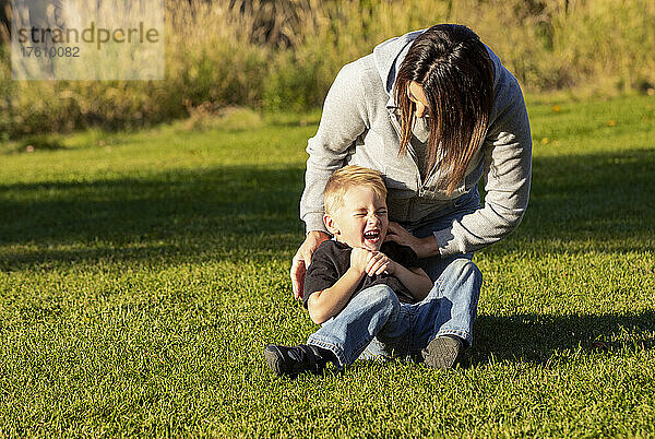 Mutter und kleiner Sohn toben auf dem Rasen eines Stadtparks; St. Albert  Alberta  Kanada