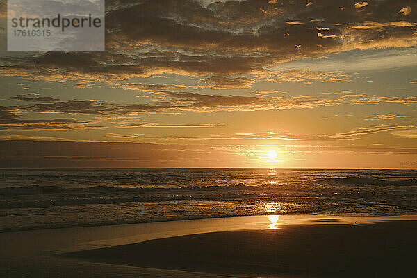 Ein goldener Sonnenuntergang spiegelt sich auf dem nassen Sand des Munggu Beach  Bali; Munggu  Bali  Indonesien