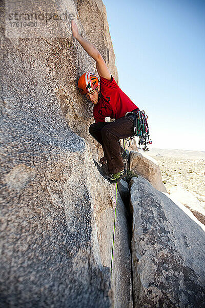 Ein Kletterer balanciert seinen Körper aus  um einen höheren Halt zu erreichen.
