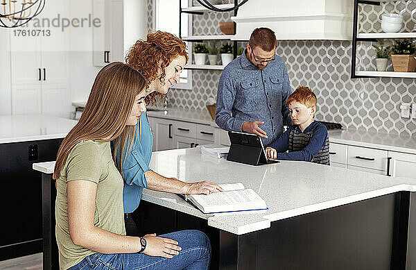 Eltern helfen ihrem Sohn und ihrer Tochter im Teenageralter bei den Hausaufgaben in der heimischen Küche; Edmonton  Alberta  Kanada