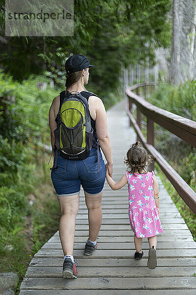 Mutter und kleine Tochter halten sich an den Händen und gehen gemeinsam einen Wanderweg im Smuggler Cove Marine Provincial Park an der Sunshine Coast von BC  Kanada; British Columbia  Kanada