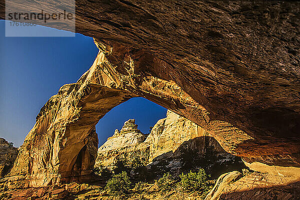 Unter der Hickman Natural Bridge mit Blick durch den Bogen auf die Sandsteinklippen im Capitol Reef National Park; Utah  Vereinigte Staaten von Amerika