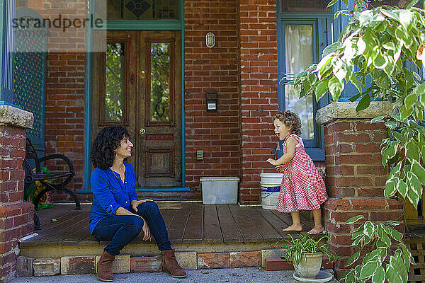Mutter und kleine Tochter sitzen vor der Haustür ihres Hauses und verbringen Zeit miteinander; Toronto  Ontario  Kanada