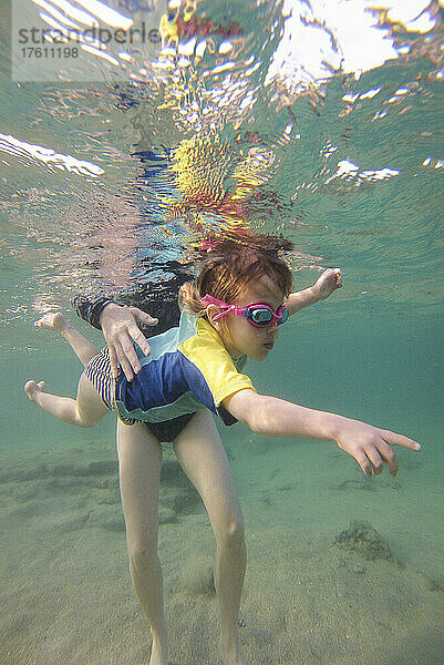 Ein dreijähriges Mädchen  das mit seiner Mutter unter Wasser schwimmt; Shacks Beach  Aquadilla  Puerto Rico.