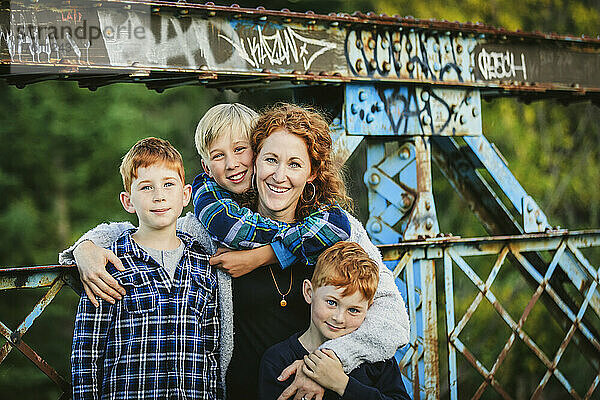 Porträt einer Mutter mit drei Jungen auf einer Brücke in einem Park im Herbst; Edmonton  Alberta  Kanada