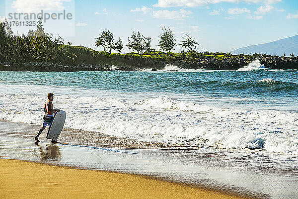 Mann geht mit einem Bodyboard am D. T. Fleming Beach auf die Wellen zu; Kapalua  Maui  Hawaii  Vereinigte Staaten von Amerika