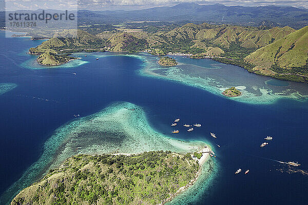 Luftaufnahme von Booten  die an der Küste einer Insel im Komodo-Nationalpark  der Heimat des berühmten Komodowarans  vertäut sind; Ost-Nusa Tenggara  Kleine Sunda-Inseln  Indonesien
