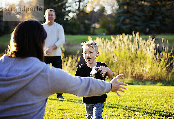 Junge Familie spielt an einem schönen Herbsttag im Park mit einem Fußball; St. Albert  Alberta  Kanada