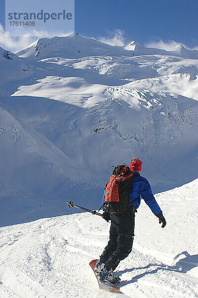 Ein Backcountry-Snowboarder fährt ein Schneefeld in Richtung eines Gletschers hinunter; Selkirk Mountains  British Columbia  Kanada.