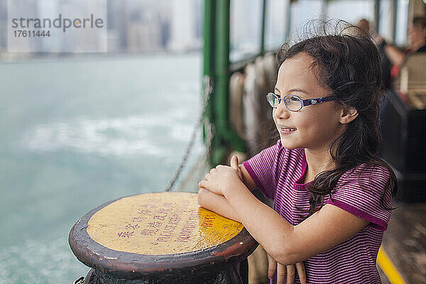 Junges Mädchen  das auf der Star Ferry steht und während einer Überfahrt über den Victoria Harbour zwischen Hongkong Island und Kowloon hinausschaut; Hongkong  China