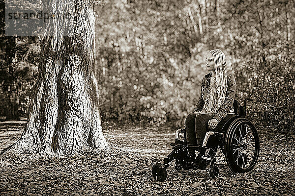Eine junge querschnittsgelähmte Frau in ihrem Rollstuhl in einem Park an einem schönen Herbsttag; Edmonton  Alberta  Kanada