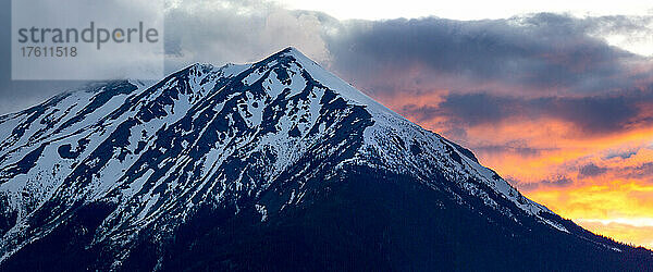 Zerklüfteter  schneebedeckter Gipfel des Hudson Bay Mountain mit bunt leuchtenden Wolken; Smithers  British Columbia  Kanada